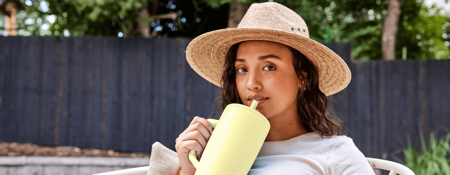 Woman in hat sipping from a 100% Leakproo Era Tumbler