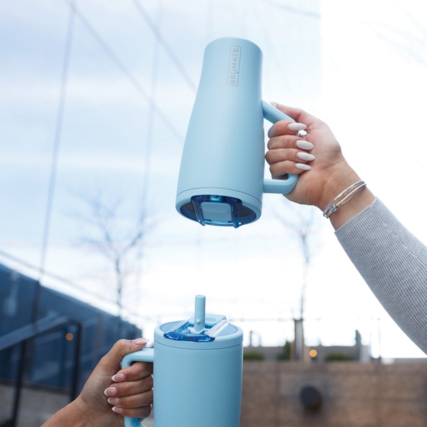 Person holding a blue Era Flip 30oz tumbler with a straw lid outdoors