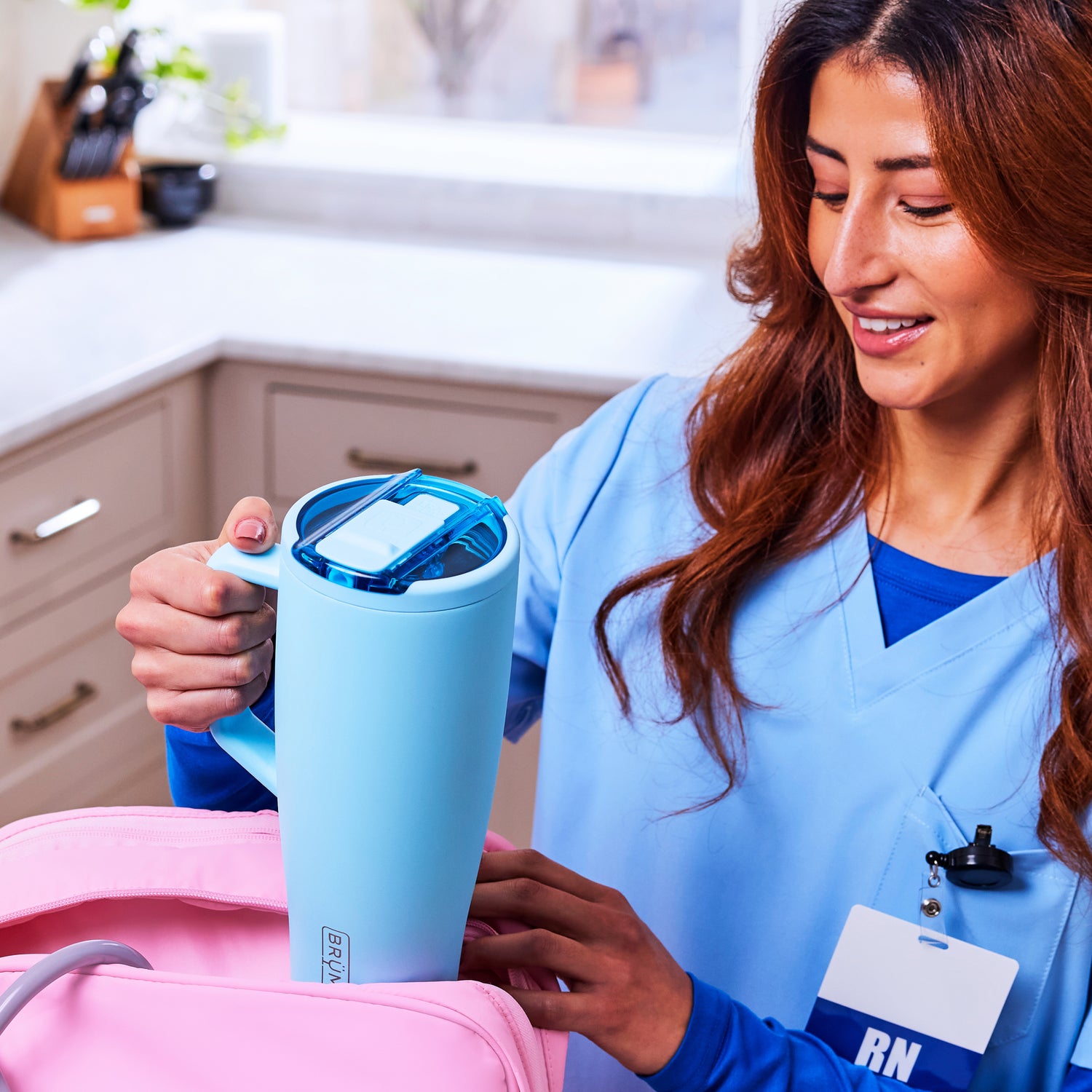 Person in blue scrubs holding a light blue Era Flip 40oz tumbler in a kitchen setting