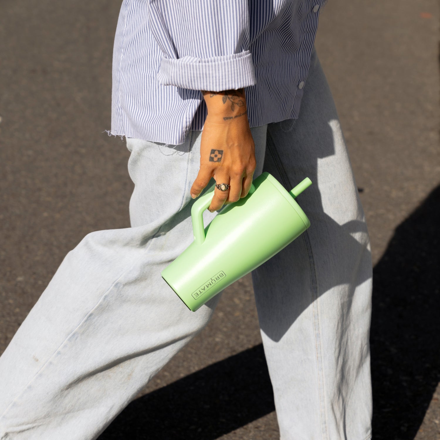 Person walking with a green Era 30oz straw tumbler