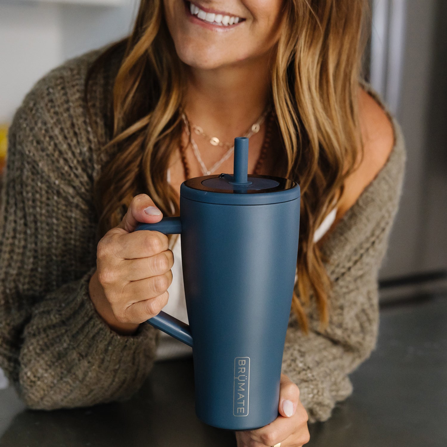 Woman holding a blue Era 30oz tumbler with a straw lid, smiling.
