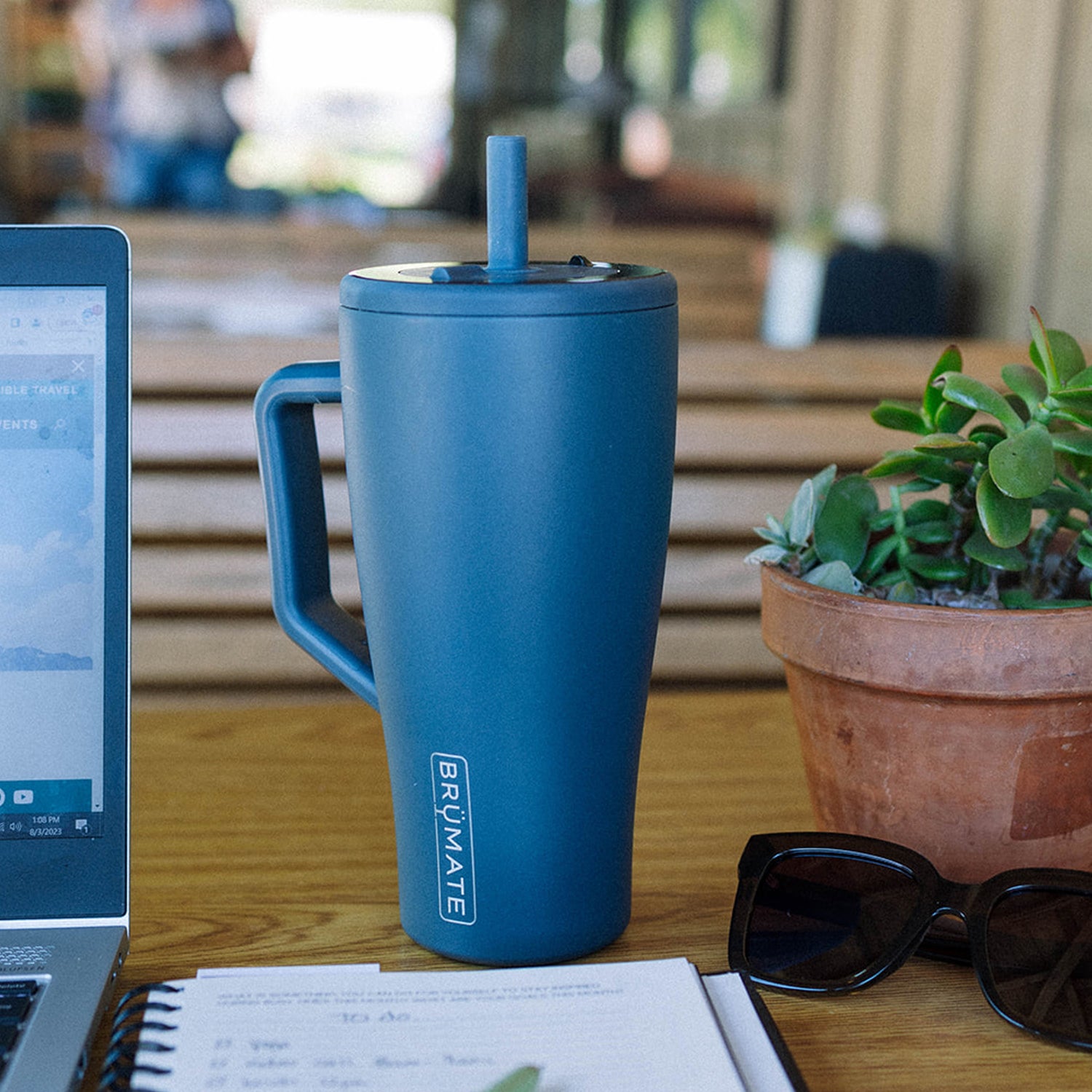 Blue Era 30oz tumbler with handle on a desk next to a laptop, sunglasses and plant