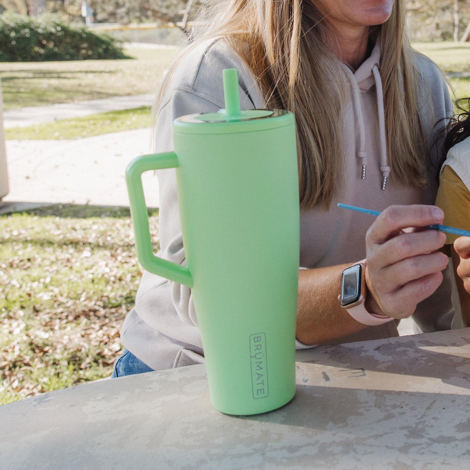 Person sitting outdoors with a green Era 40oz tumbler 