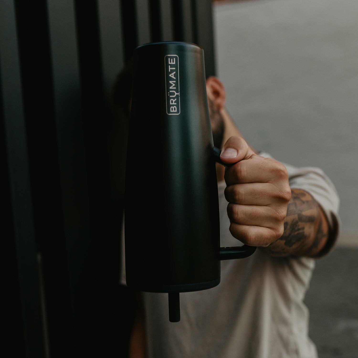 Person holding a black Brumate Era 40oz tumbler upside down against a dark background