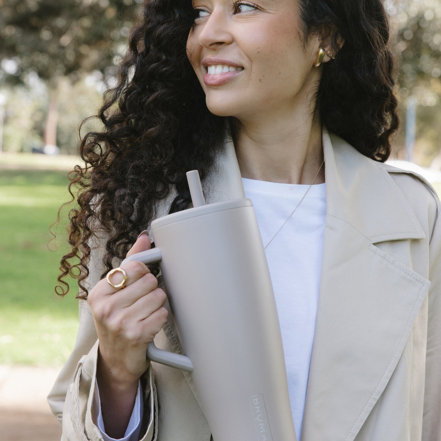 Woman holding a beige Era 40oz tumbler outdoors with a blurred natural background