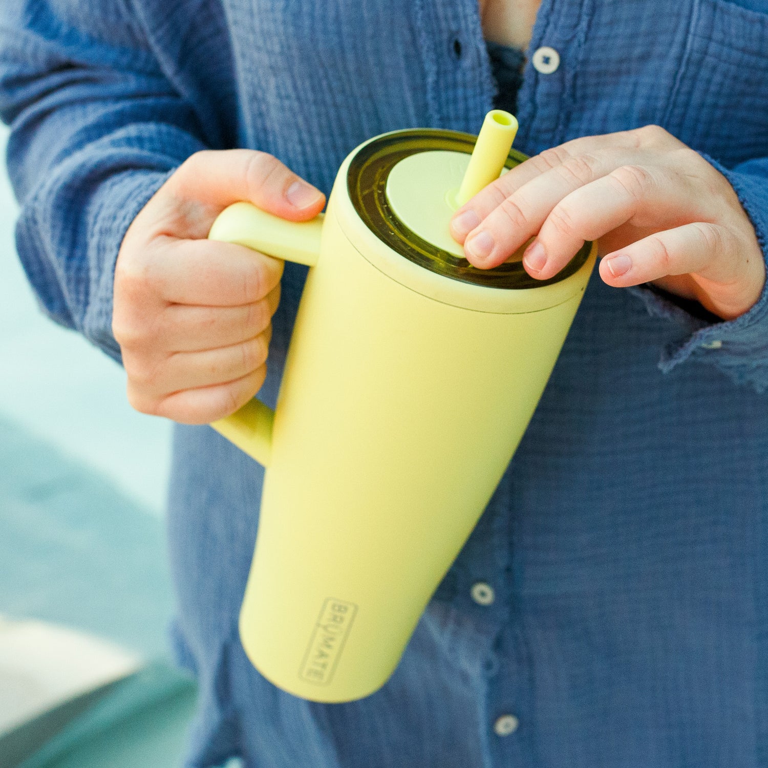 Person holding a yellow Era 40oz tumbler with a straw, wearing a blue shirt.