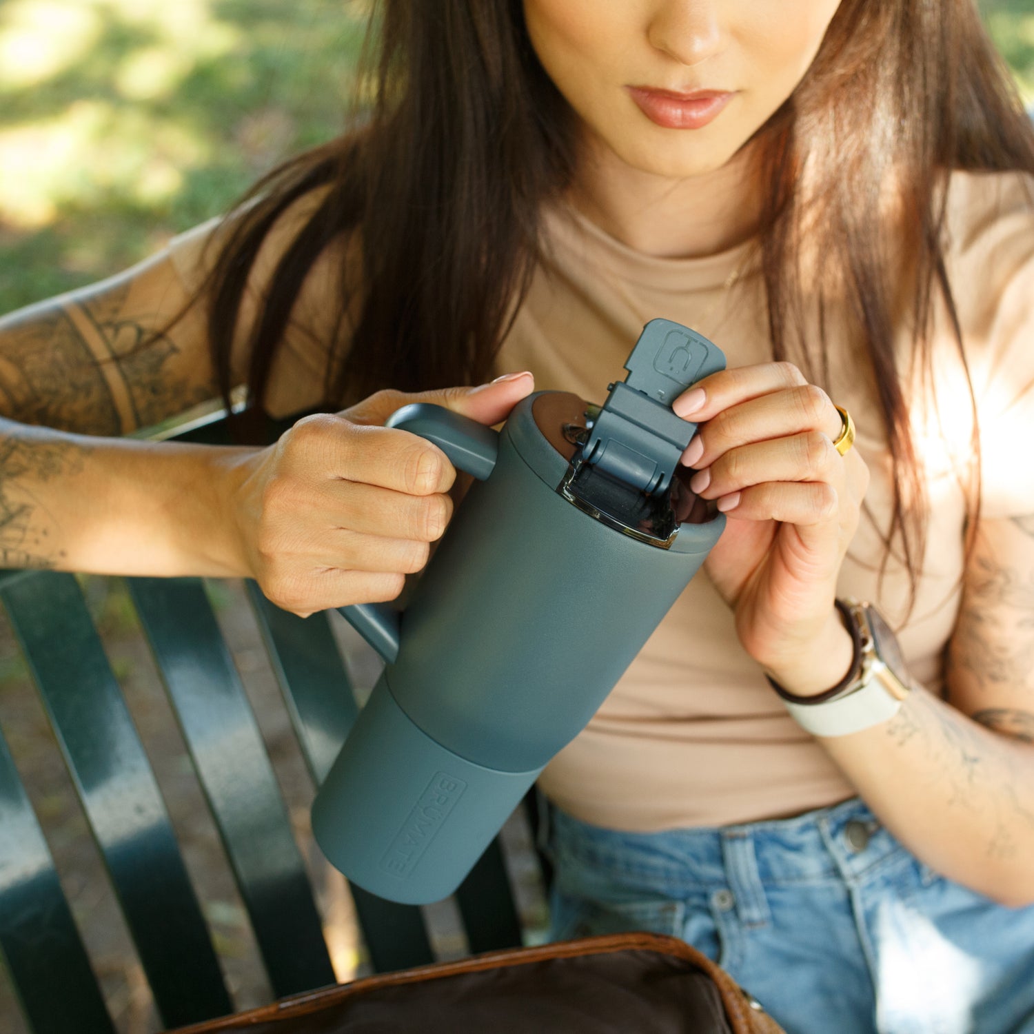 Person holding a blue Muv 25oz mug outdoors