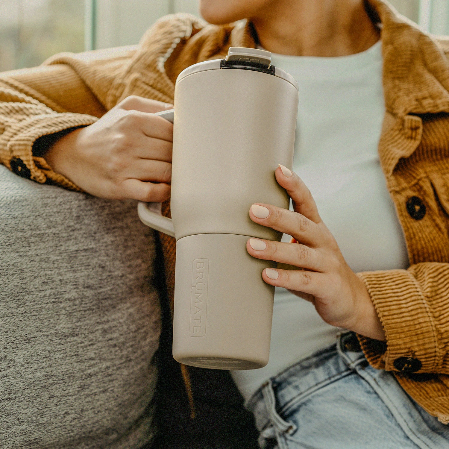 Person holding a beige Muv 35oz tumbler with a blurred background
