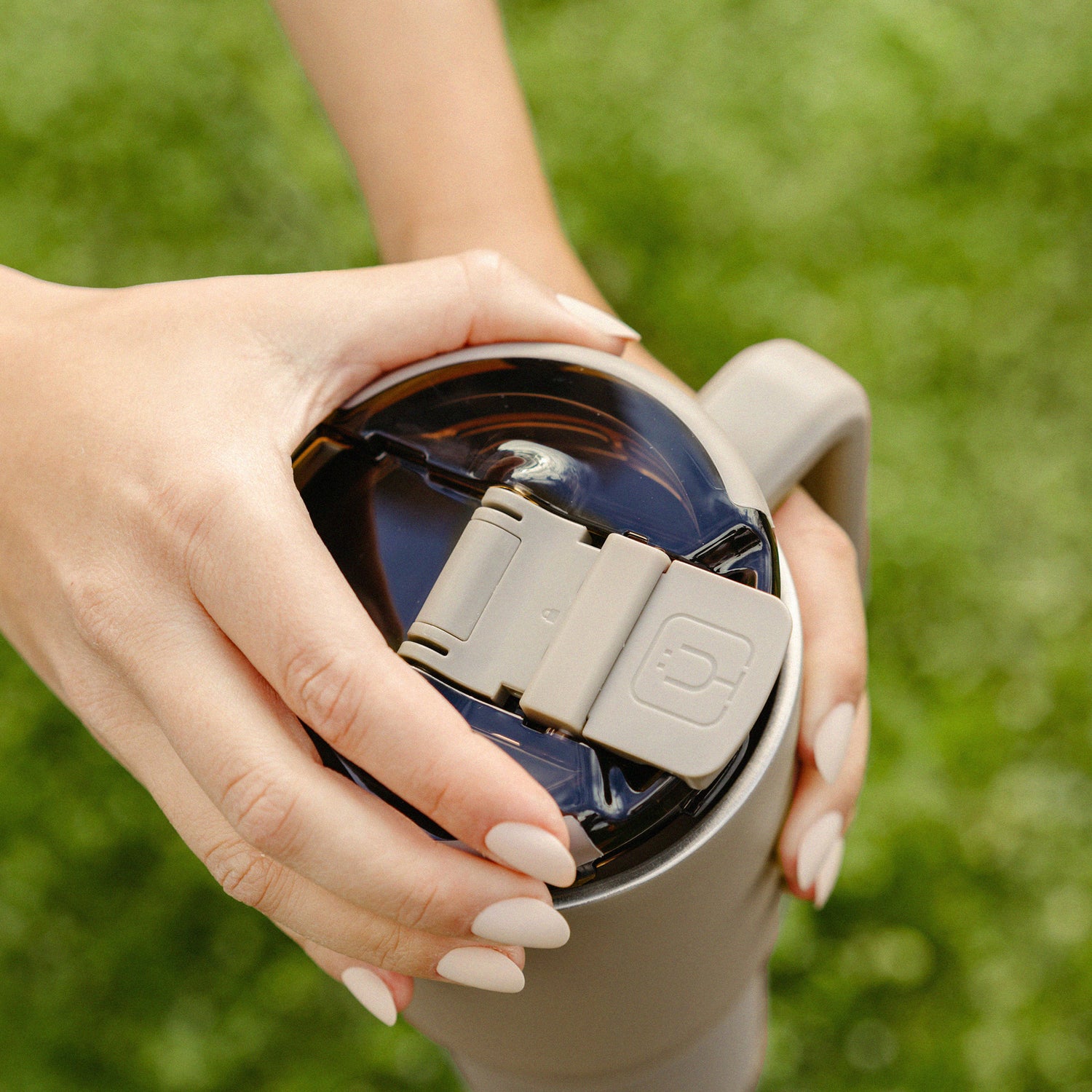 Person holding a beige Muv 35oz against a green blurred background