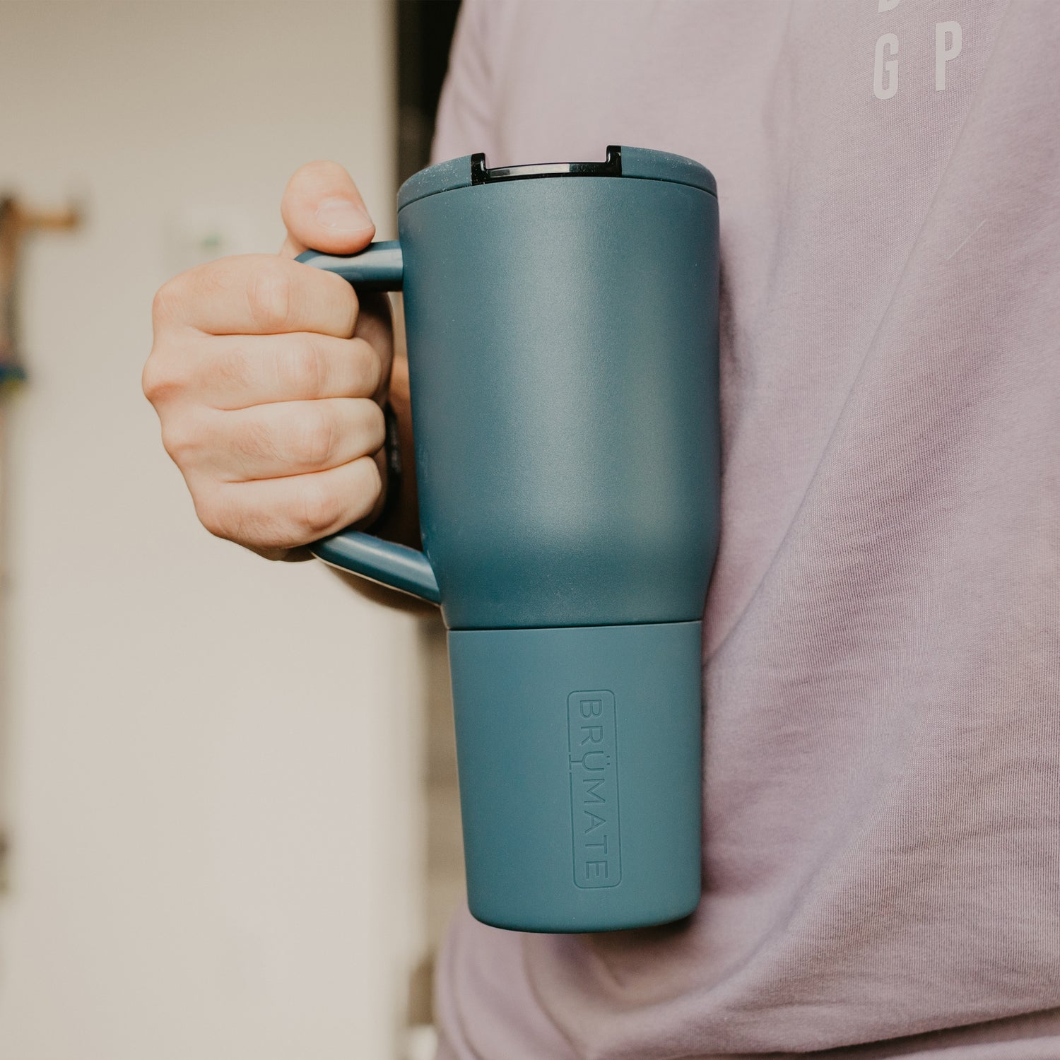 Person holding a blue Muv 35oz tumbler against a neutral background