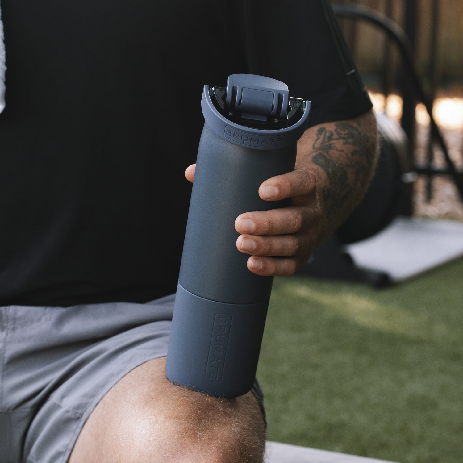 Person holding a blue Rise 25oz water bottle outdoors
