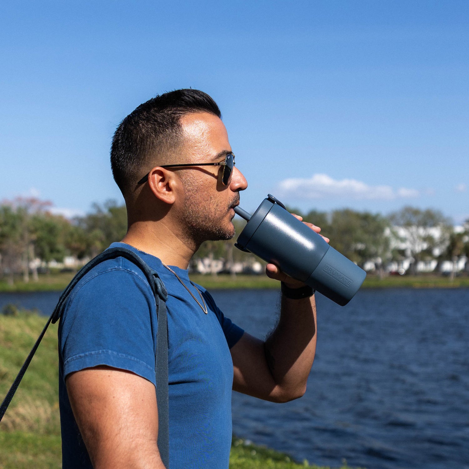 Man drinking from a blue Resa 25oz tumbler by a lake