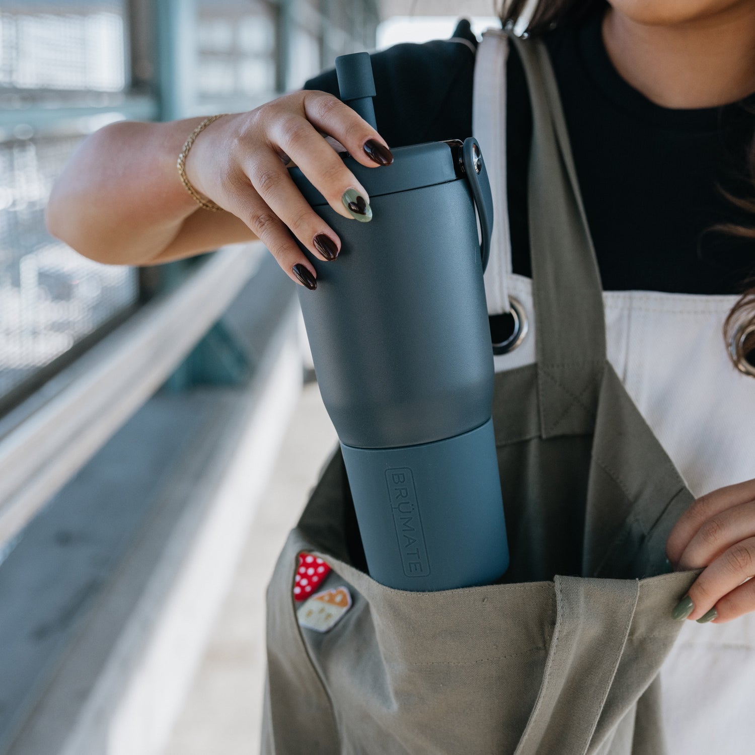 Person holding a blue Resa 25oz tumbler in an open bag with a blurred background
