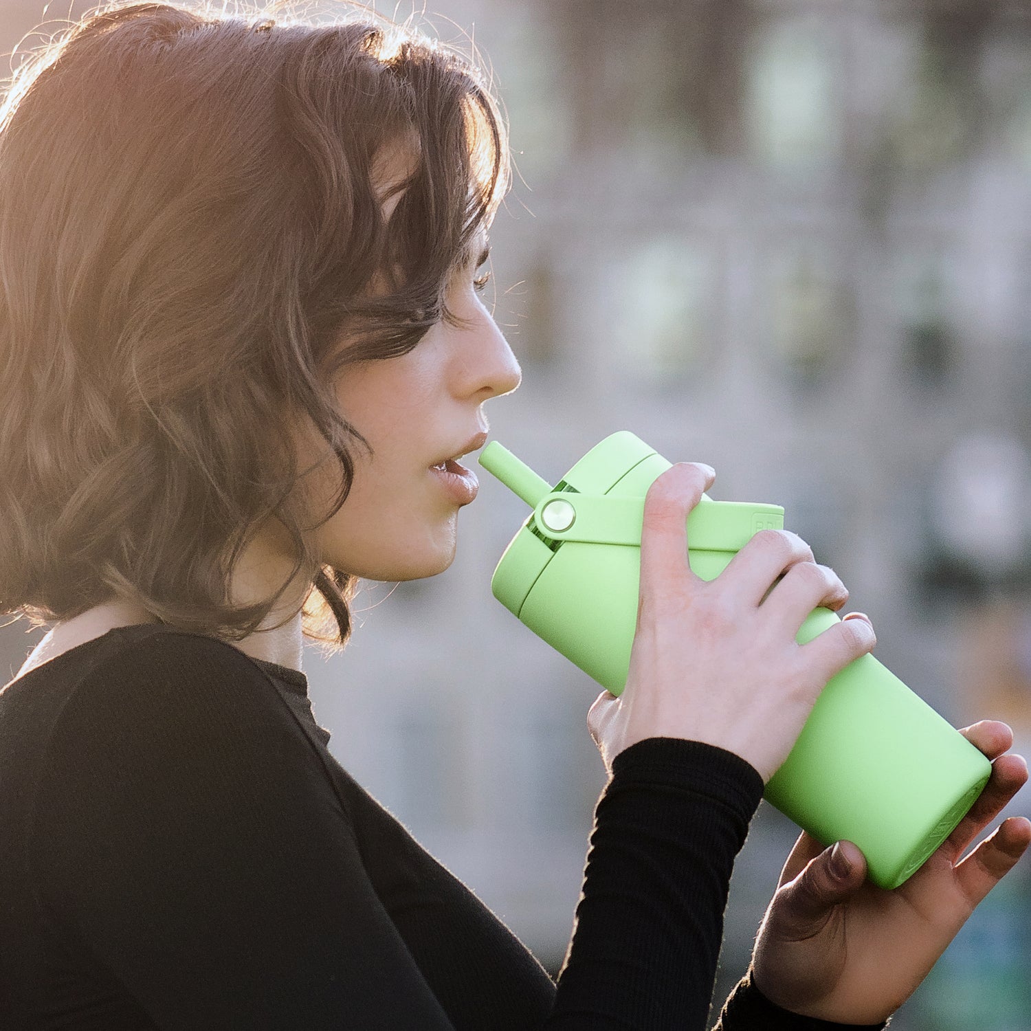 Person holding a green Resa 35oz tumbler with a straw outdoors