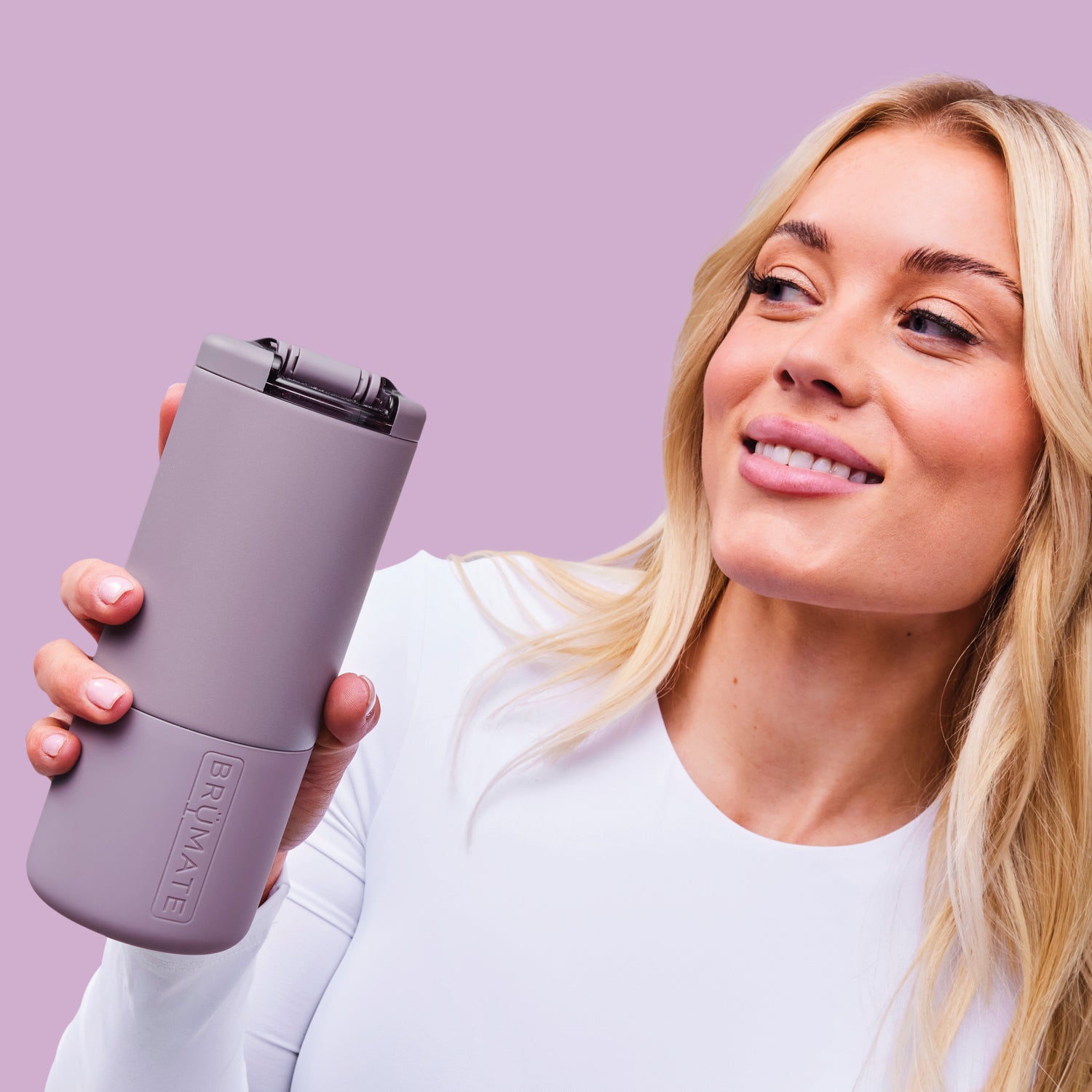 Woman holding a purple Strova 18oz coffee tumbler with a purple background