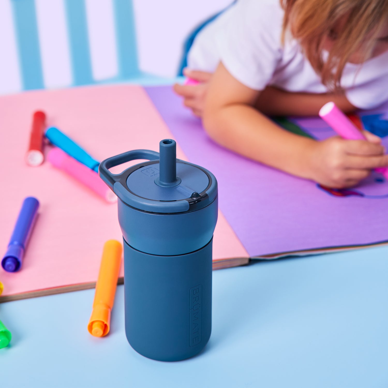Blue Leap 12oz tumbler with a child drawing in the background